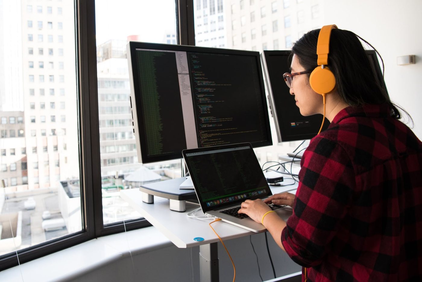 Software developer writing code across multiple monitors
