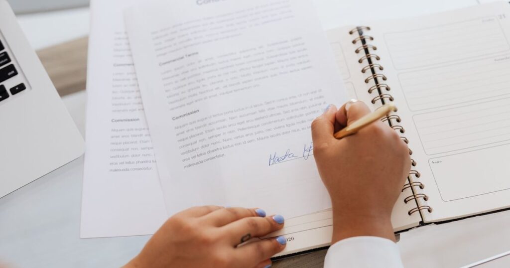 Person signing a contract at a desk