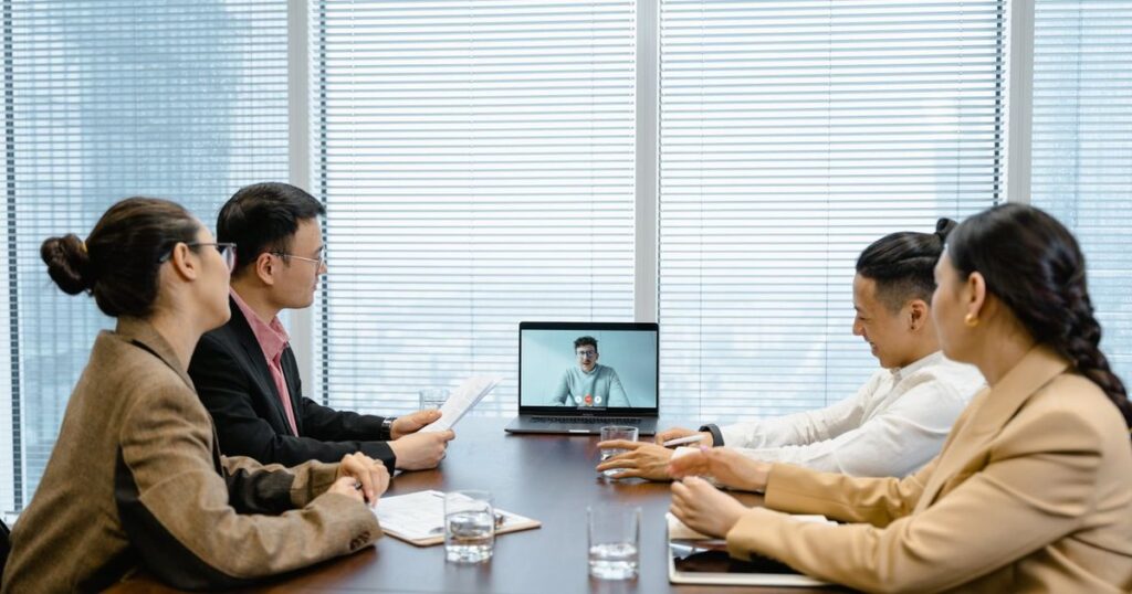Colleagues in a meeting room on a video call with a remote team member