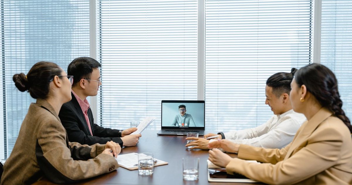 Colleagues in a meeting room on a video call with a remote team member